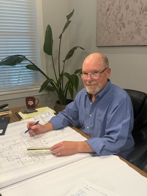 David Young at his desk reviewing a set of house plans