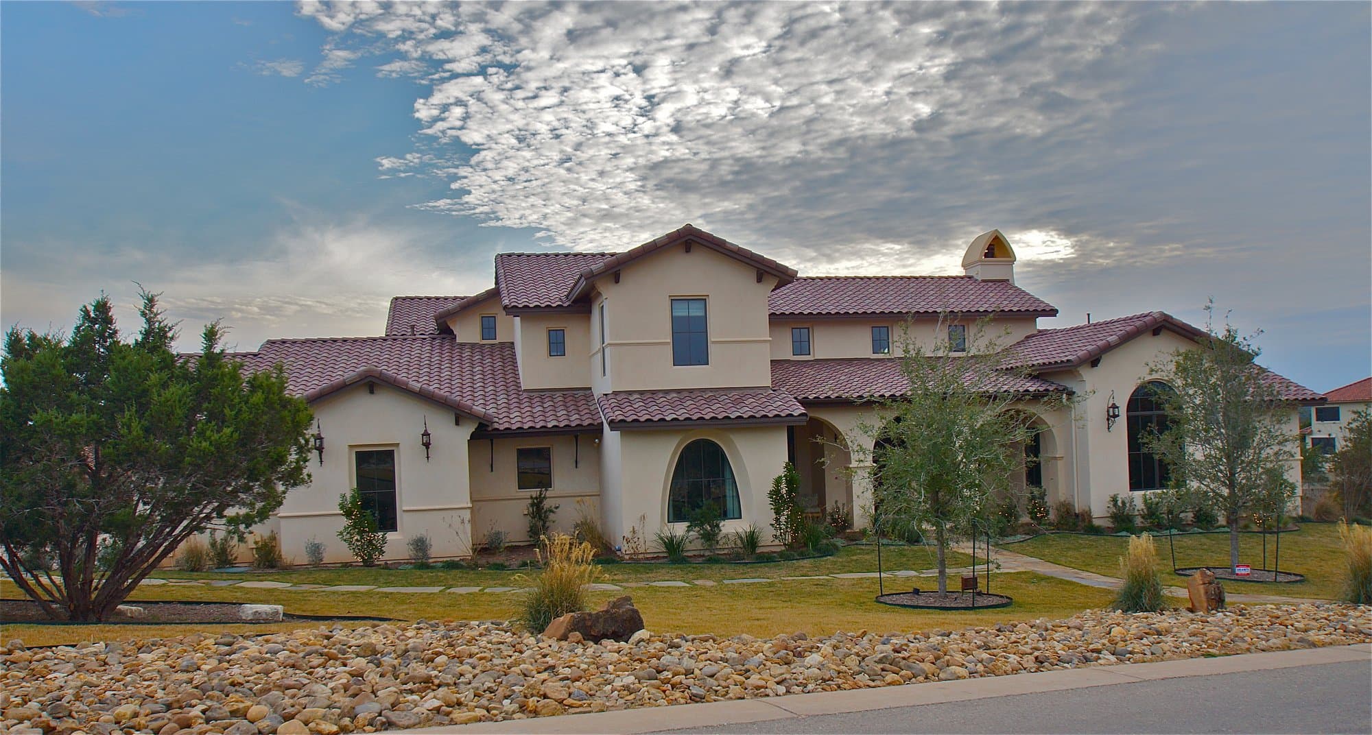 Two-story Mediterranean villa with stucco walls, a red tile roof and arched windows