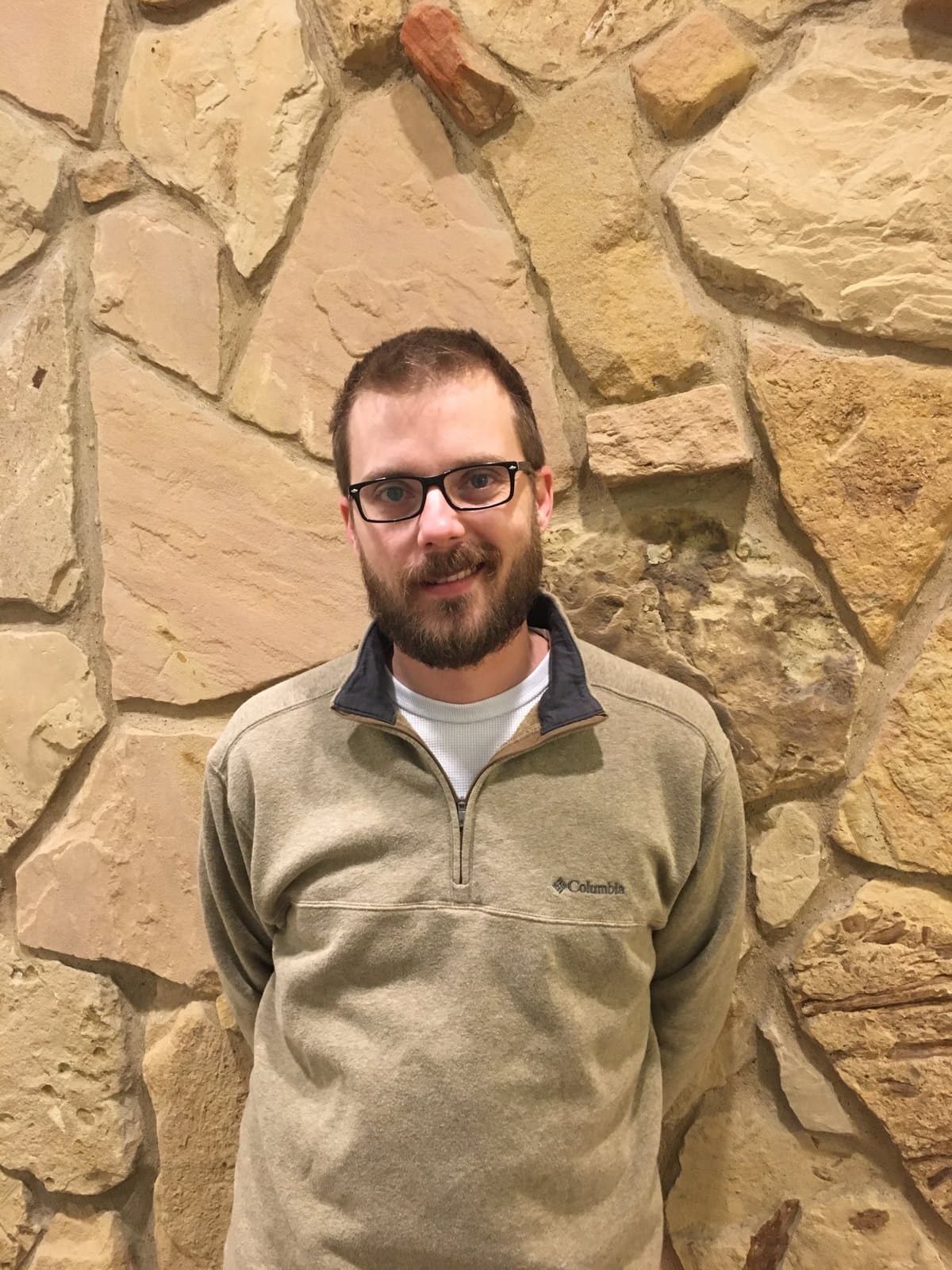Sam Young standing in front of a Texas limestone wall